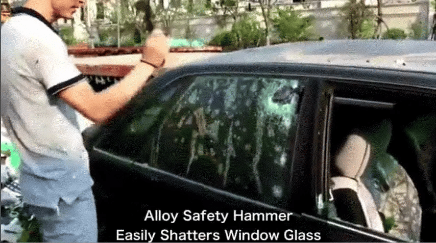 Person using a safety hammer to shatter a car side window, with caption that it easily shatters glass