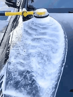 Car hood covered in thick foam from a yellow car wash tool