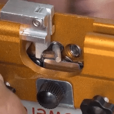 Close-up of the orange sharpening jig clamping a saw chain, with a knurled adjustment knob