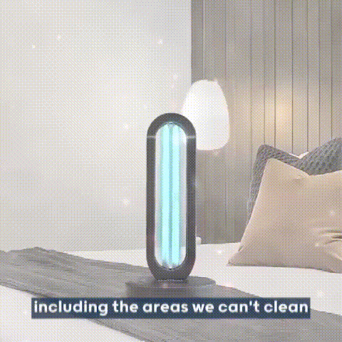 UV sanitizer lamp with a glowing blue tube standing on a bed beside pillows