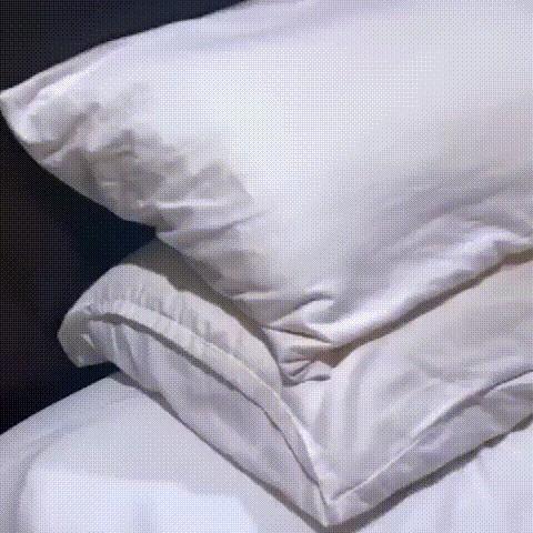 Stacked white pillows and crisp white bedding on a bed