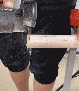 Mini grinder cutting a round wooden dowel in a workshop