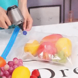 Handheld vacuum nozzle at the valve of a clear plastic bag of fruit
